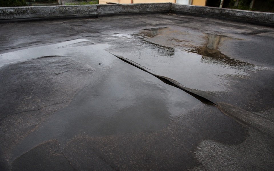 Agua embalsada sobre una lámina impermeabilizante deteriorada